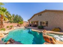Inviting backyard pool and spa with lush landscaping, outdoor seating, and a covered patio at 44158 W Canyon Creek Dr, Maricopa, AZ 85139