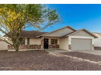 Charming single-story home featuring a desert landscape, two-car garage, and stone accents at 6244 E Inglewood St, Mesa, AZ 85205