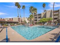 Resort-style pool with sun loungers and lush palm trees offers a relaxing community space at 7625 E Camelback Rd # B244, Scottsdale, AZ 85251