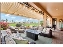 Inviting covered patio with wicker furniture and a cozy fireplace, perfect for outdoor gatherings and enjoying the golf course view at 16077 W Vale Dr, Goodyear, AZ 85395