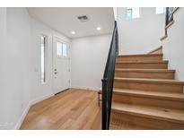 Inviting entryway featuring light wood floors, white walls, and a modern staircase with a black railing at 5537 E Earll Dr, Phoenix, AZ 85018