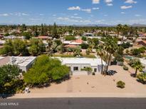 Expansive aerial view of a modern white home with desert landscaping, a gated entry, and distant mountain views at 6102 E Friess Dr, Scottsdale, AZ 85254