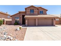 Two-story home with a red tile roof, three-car garage and low-maintenance desert landscaping at 7179 W Surrey Ave, Peoria, AZ 85381