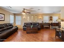Inviting living room featuring wood floors, comfortable leather seating, and a piano at 8259 W Carol Ave, Peoria, AZ 85345