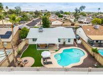 Aerial view of a backyard featuring a pool, covered patio with table, and fire pit with lounge chairs at 19414 N 3Rd Ave, Phoenix, AZ 85027