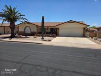 Charming single-story home featuring a well-maintained lawn and a desert-themed landscape with a palm tree at 8303 E Meseto Ave, Mesa, AZ 85209