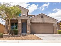 Charming two-story home featuring a well-manicured lawn, tree, and an attached two-car garage at 8924 N 102Nd Ln, Peoria, AZ 85345