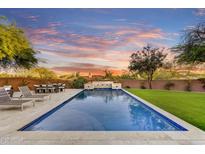 Inviting pool with sleek stone accents, lush landscaping, and relaxing lounge chairs under a beautiful Arizona sunset at 9669 E Chino Dr, Scottsdale, AZ 85255