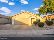 Charming single-story home featuring a well-manicured front yard with lush landscaping and a two-car garage at 14211 N 149Th Dr, Surprise, AZ 85379