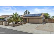 Charming home featuring solar panels, a two-car garage, and a lovely front yard with a palm tree at 17244 N 29Th Ave, Phoenix, AZ 85053