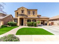 Elegant two-story home with arched entryway, manicured lawn, and covered parking at 20366 E Via De Colina --, Queen Creek, AZ 85142