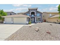 Stunning two-story home with a three-car garage and low-maintenance desert landscaping in front yard at 553 E Baylor Ln, Gilbert, AZ 85296