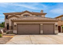 Traditional two-story home with a large three car garage and desert landscaping in the front at 5993 W Topeka Dr, Glendale, AZ 85308