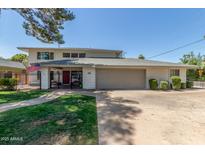Two-story home features a red door, gray garage door, brick pathway, and manicured lawn at 8464 N 7Th Ave, Phoenix, AZ 85021