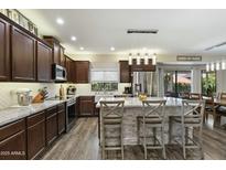 Well-lit kitchen featuring wood floors, cabinets, stainless appliances, and island with bar seating at 16202 N 61St Ave, Glendale, AZ 85306