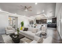 Bright living room with modern furnishings that flows into the kitchen with dark wood cabinets at 1712 E Joelle Dr, Casa Grande, AZ 85122