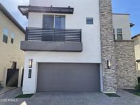 Modern two-story home with a gray garage door, stone accent wall, and a second story balcony at 1840 S Follett Way, Gilbert, AZ 85295