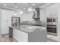Modern kitchen with stainless steel appliances, large island and mosaic tile backsplash at 1848 S Follett Way, Gilbert, AZ 85295
