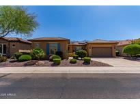 Charming single-story home boasts meticulously landscaped front yard, attached garage and solar panels, under a bright blue sky at 20283 N 273Rd Ave, Buckeye, AZ 85396