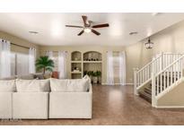 Bright, open-concept living room with large sectional sofa and elegant staircase at 4516 W Fortune Dr, Phoenix, AZ 85086