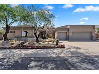 Stunning home exterior with desert landscaping, mature trees, and a spacious three-car garage at 6184 E Dusty Coyote Cir, Scottsdale, AZ 85266