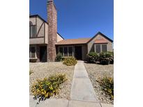 Charming townhome with manicured gravel yard, vibrant yellow flowers, and a brick chimney at 7905 W Thunderbird Rd # 305, Peoria, AZ 85381