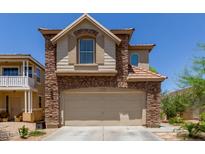 Two-story home featuring a stone facade and arched garage entrance with a concrete driveway at 13420 W Berridge Ln, Litchfield Park, AZ 85340