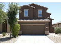 Two-story home with brown stucco, a concrete driveway, and attached two-car garage, and some landscaping at 20217 W Desert Bloom St, Buckeye, AZ 85326