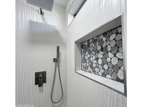 Modern shower featuring textured tile walls, pebble-style accents, and contemporary fixtures at 22261 W Tonto St, Buckeye, AZ 85326