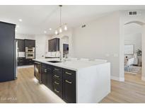 Modern kitchen with an island, dark cabinets, stainless steel appliances, and a stylish pendant light at 3202 E Orange Dr, Phoenix, AZ 85018