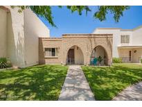 Charming townhome exterior with brick accents, grassy lawn, and covered porch entry at 7808 E Lewis Ave, Scottsdale, AZ 85257