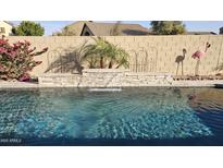 Inviting pool area with a stacked stone waterfall feature, pink flamingo, and lush landscaping at 28093 N Pasture Canyon Dr, San Tan Valley, AZ 85143
