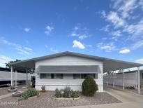 Well maintained manufactured home with desert landscaping, covered parking and sunshades, under a beautiful blue sky at 305 S Val Vista Dr # 243, Mesa, AZ 85204