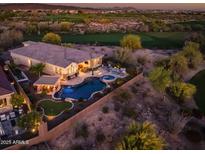 Stunning aerial view of the house and backyard featuring a pool, putting green, and desert landscaping at sunset at 31108 N 122Nd Ln, Peoria, AZ 85383