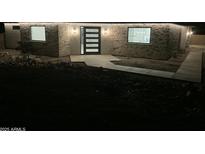 Modern home exterior featuring stone accents, well lit walkway, and a contemporary front door at dusk at 4079 E Roosevelt St, Apache Junction, AZ 85119