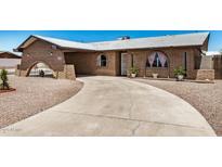 Lovely front of brick home with arch detail over carport and desert landscaping at 6430 W Thomas Rd, Phoenix, AZ 85033