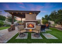 Inviting outdoor living space with a stone fireplace, pergola, and comfortable seating for relaxing evenings at 7230 W Pershing Ave, Peoria, AZ 85381
