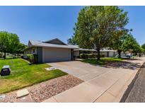 Charming single-story home featuring a spacious driveway, two-car garage, mature trees, and well-maintained lawn at 12719 W Ashwood Dr, Sun City West, AZ 85375