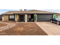 Charming single-story home with a black two-car garage and desert rock landscaping at 4441 W Windrose Dr, Glendale, AZ 85304