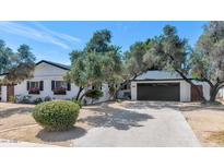 Charming single-story home with a manicured yard and a two-car garage under a clear blue sky at 6207 E Rose Circle Dr, Scottsdale, AZ 85251