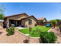 A well-maintained backyard with artificial turf, desert landscaping and covered patio at 7015 W Melody Dr, Laveen, AZ 85339