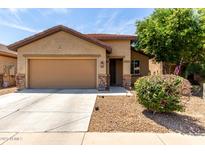 Charming single-Gathering home featuring a two-car garage, desert landscaping, and a covered entryway at 7015 W Melody Dr, Laveen, AZ 85339