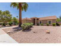 Tan single-story home featuring a tile roof, neutral desert landscaping, and mature palm tree in the front yard at 950 N Sailors Way, Gilbert, AZ 85234