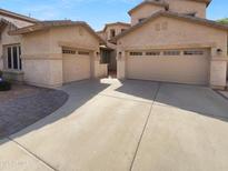 A home featuring a beige garage with two doors, complemented by a paved driveway leading to the residence at 13335 W Marlette Ct, Litchfield Park, AZ 85340