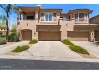Beige townhome showcasing a three-car garage and lovely desert landscaping at 16420 N Thompson Peak Pkwy # 1002, Scottsdale, AZ 85260