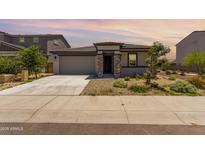 Charming single story home with a two car garage and stone accents at dusk at 18021 W Avenida Del Sol --, Surprise, AZ 85387