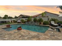 Backyard pool and waterfall feature with lush landscaping and comfortable lounging options at 41926 W Sussex Dr, Maricopa, AZ 85138