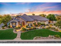 A stunning single-Gathering home has lush green landscaping, a stone facade, and a welcoming entrance at sunset at 6918 E Ivyglen St, Mesa, AZ 85207