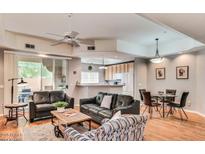 Open-concept living room with hardwood floors and modern furnishings with eat-in kitchen in the background at 8245 E Bell Rd # 103, Scottsdale, AZ 85260