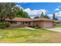 Charming single-story home featuring a brick facade, lush lawn, and well-manicured landscaping at 9805 W Gulf Hills Dr, Sun City, AZ 85351